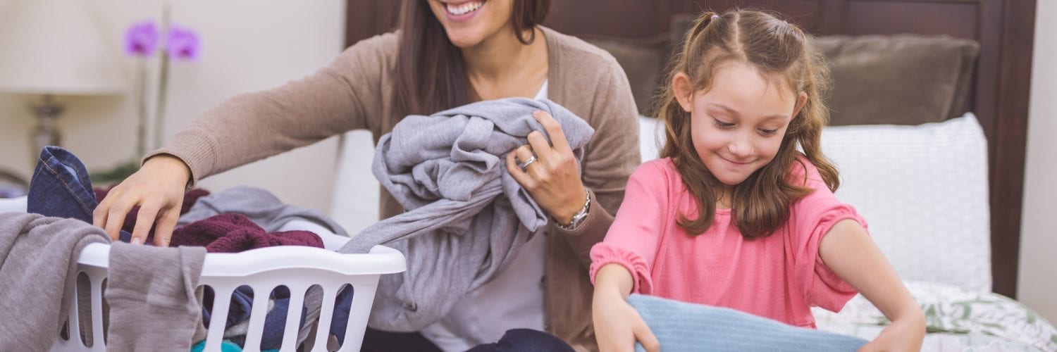 mother cheerfully folding clothes with her daughter