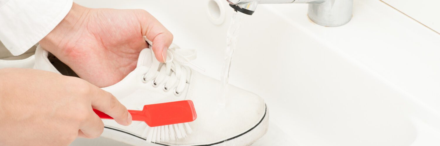red brush scrubbing white shoe